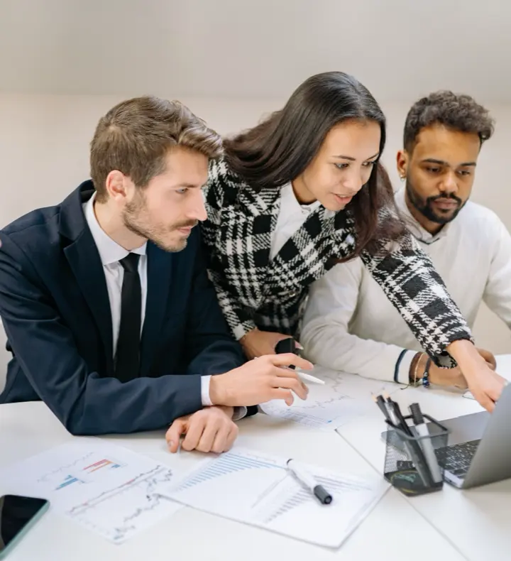 A team of professionals working together around a laptop.