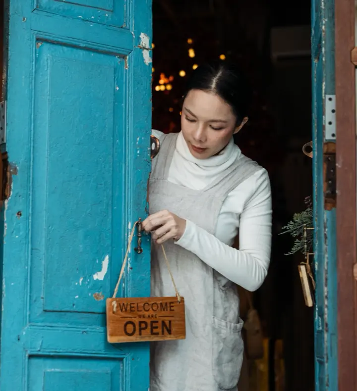 A small business owner turning the open sign on their shop door.