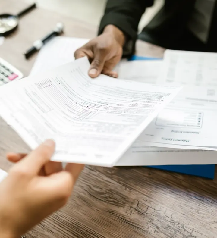Two professionals passing documents across an office desk.